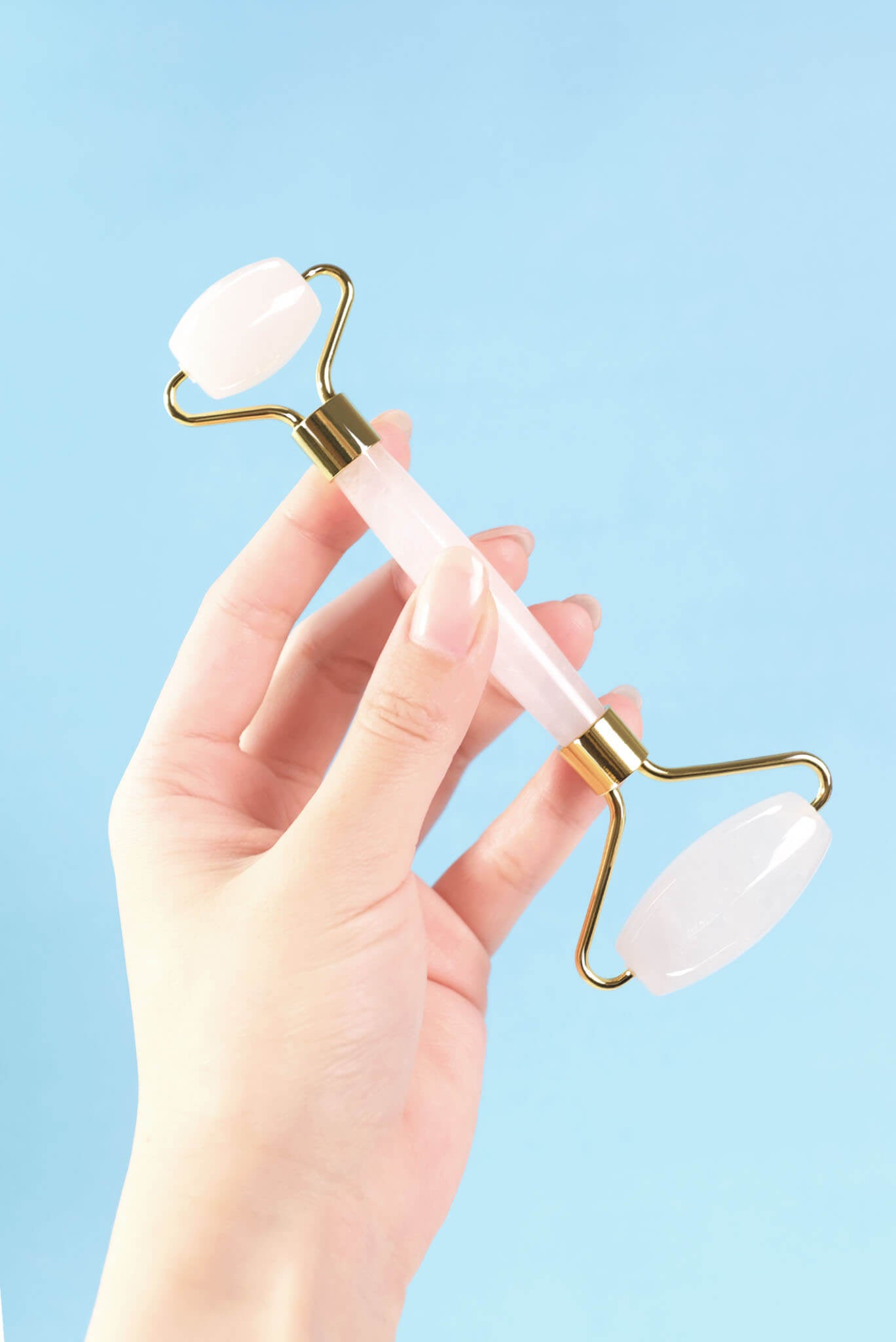 手のひらで持ったフェイスシャルローラー ミルキークォーツの画像。サイズ感と持ちやすさが分かる。